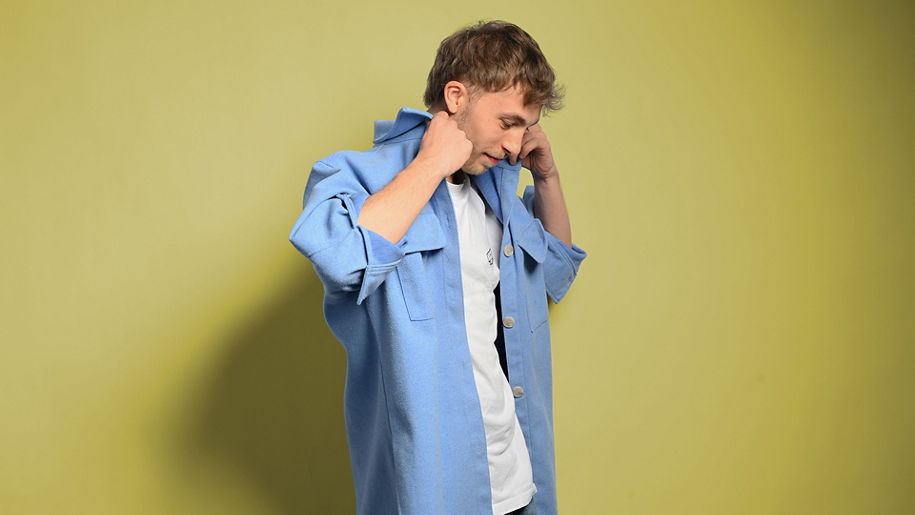 Julian schaut nach unten und richtet sein blaues Hemd