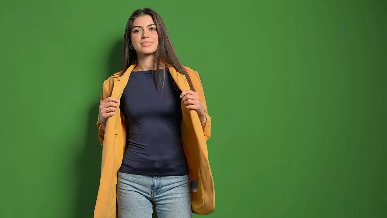 Emilia schaut in die Kamera und hält ihre Jacke