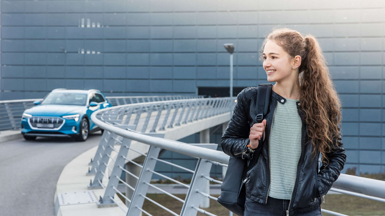 Ein Mädchen schaut lächelnd nach links und trägt einen Rucksack auf einer Schulter