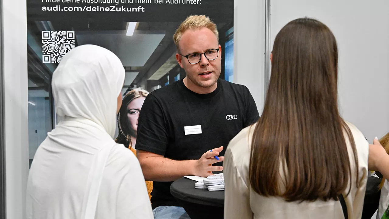 Mann mit Brille erklärt zwei Personen etwas und trägt eine Brille