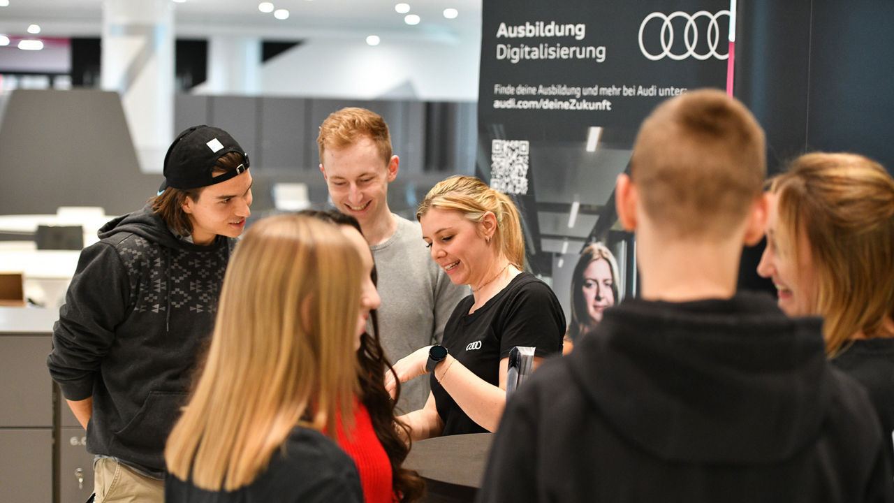 Eine Gruppe von jugendlichen Messegästen an einem Stand von Audi 