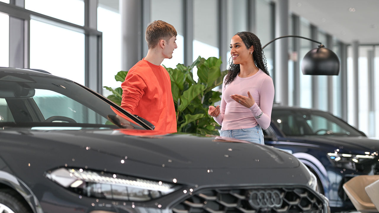Zwei Personen unterhalten sich und es steht ein Audi vor ihnen