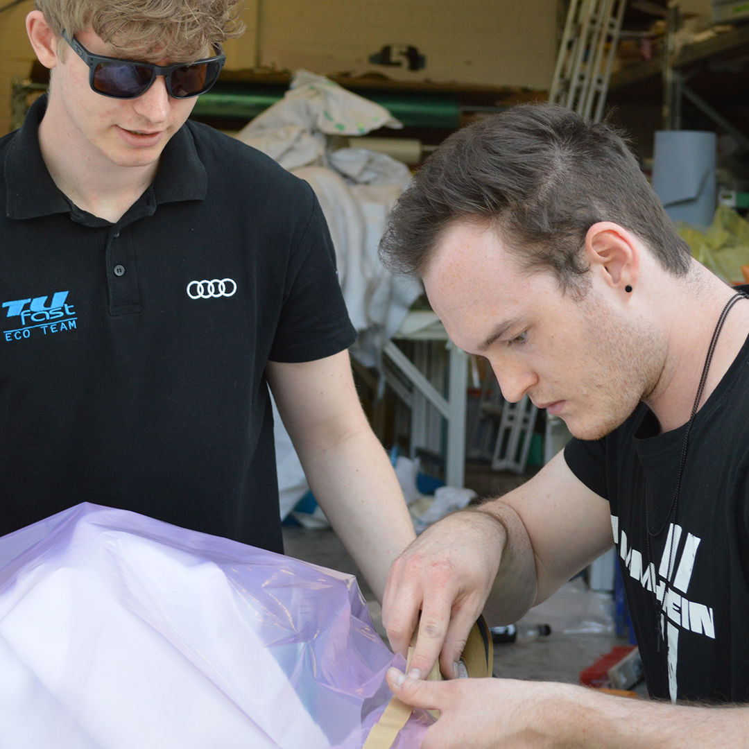 Zwei Männer kleben etwas mit einer Plastiktüte zu