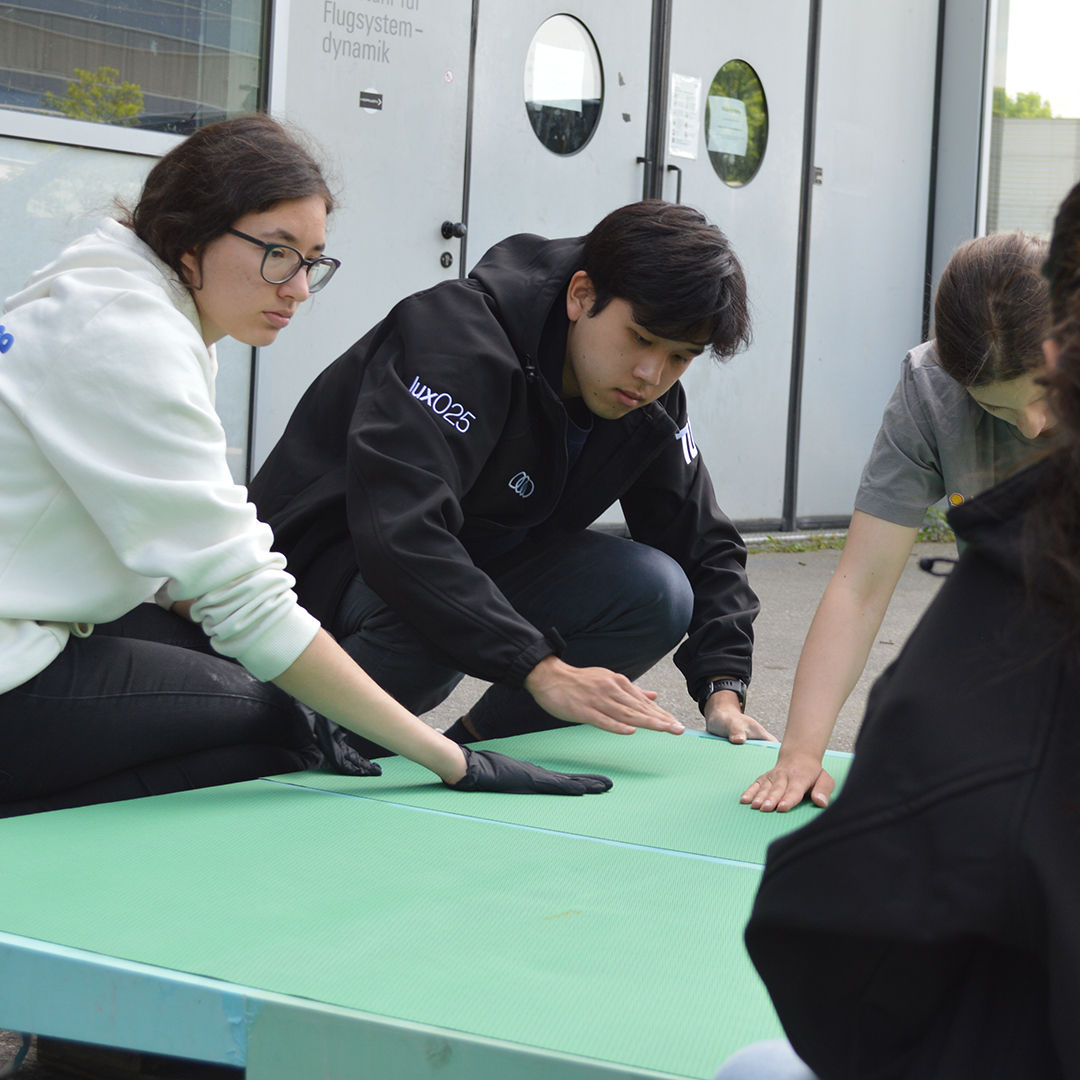 Ein paar Studenten arbeiten an einer grünen Pappe, die auf dem Boden liegt