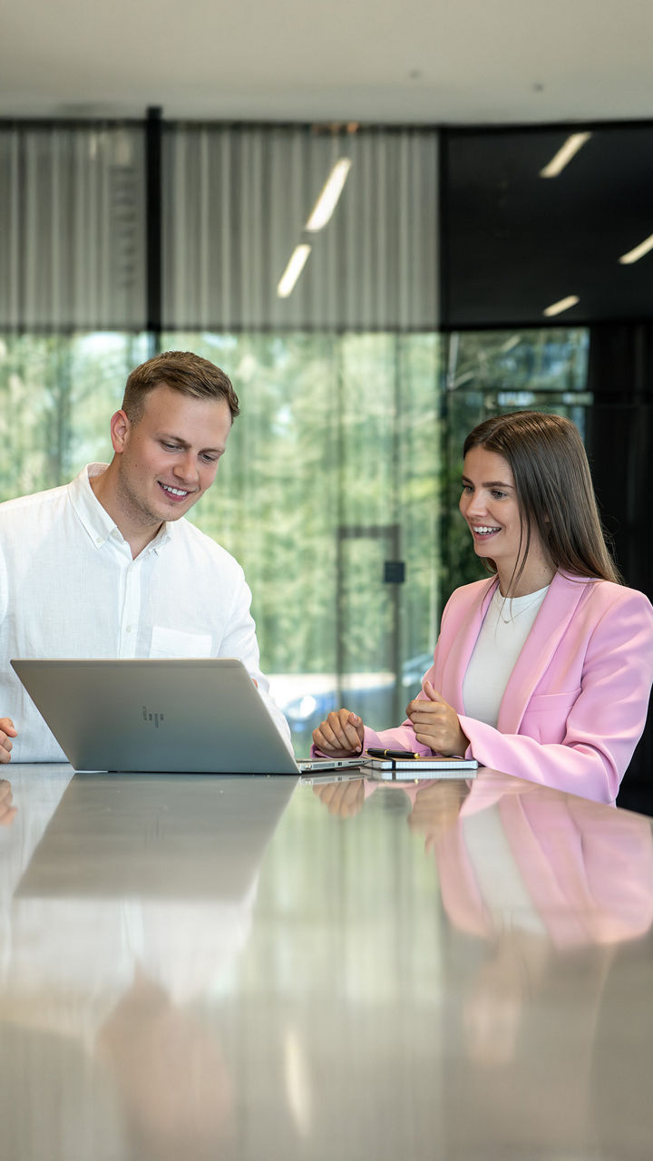 Zwei Studenten schauen sich etwas auf einem Laptop an und lächeln