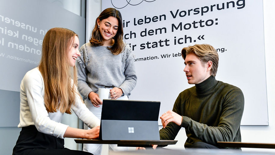 Drei Studenten sitzen an einem Tisch und reden miteinander