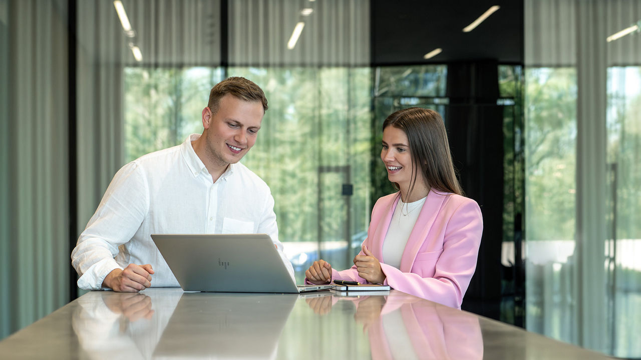Two students look at a screen of a laptop together