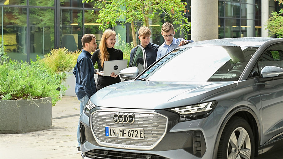 Several young adults look at an Audi model