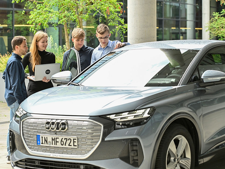 Mehrere junge Erwachsene schauen sich ein Audi Modell an