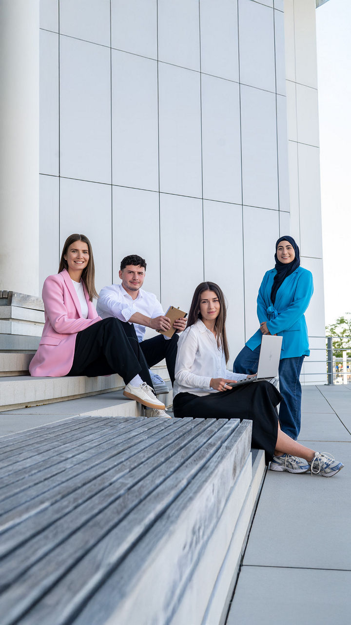 Four interns look at the camera and sit on a staircase