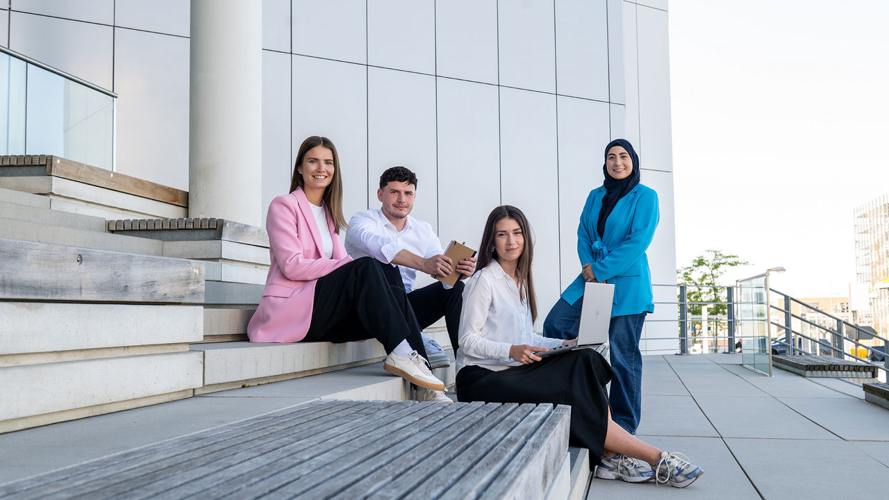 Four interns look at the camera and sit on a staircase