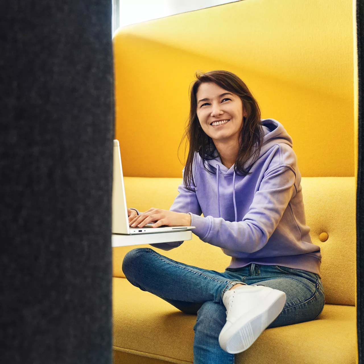 Sevgi lacht an der Kamera vorbei und hat einen Laptop vor sich