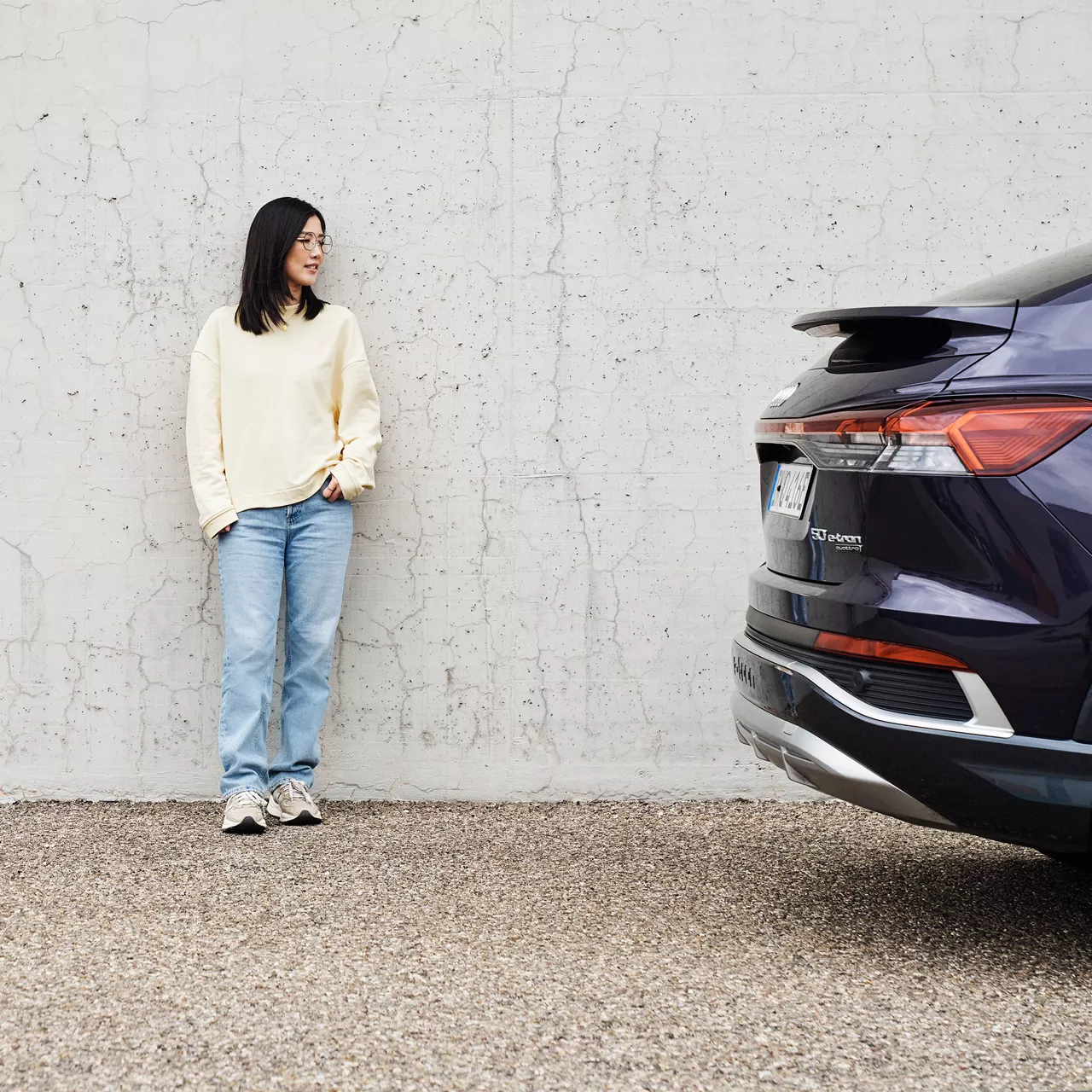 Tiantian schaut auf einen lilanen Audi und ist an eine Wand gelehnt