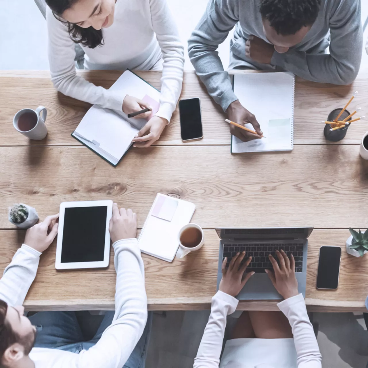 Mobile Teamarbeit am Küchentisch mit vier Personen an Laptops
