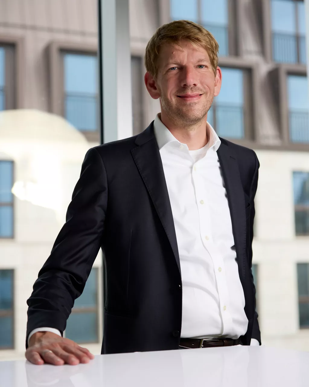 Julio Schuback, Leiter Corporate Content House der Audi Kommunikation steht vor einem Tisch und schaut in die Kamera