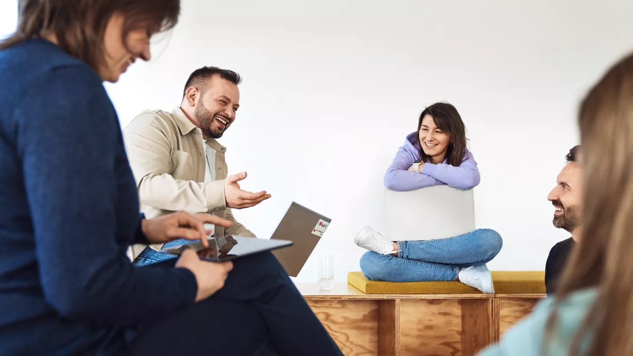 Einige Mitarbeitende sitzen im Kreis und sprechen miteinander