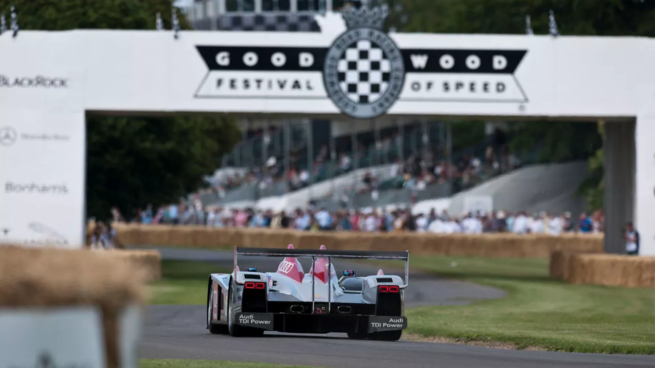 Ein Rennwagen fährt auf einer Rennstrecke unter dem Tor vom Goodwood Festival of Speed durch