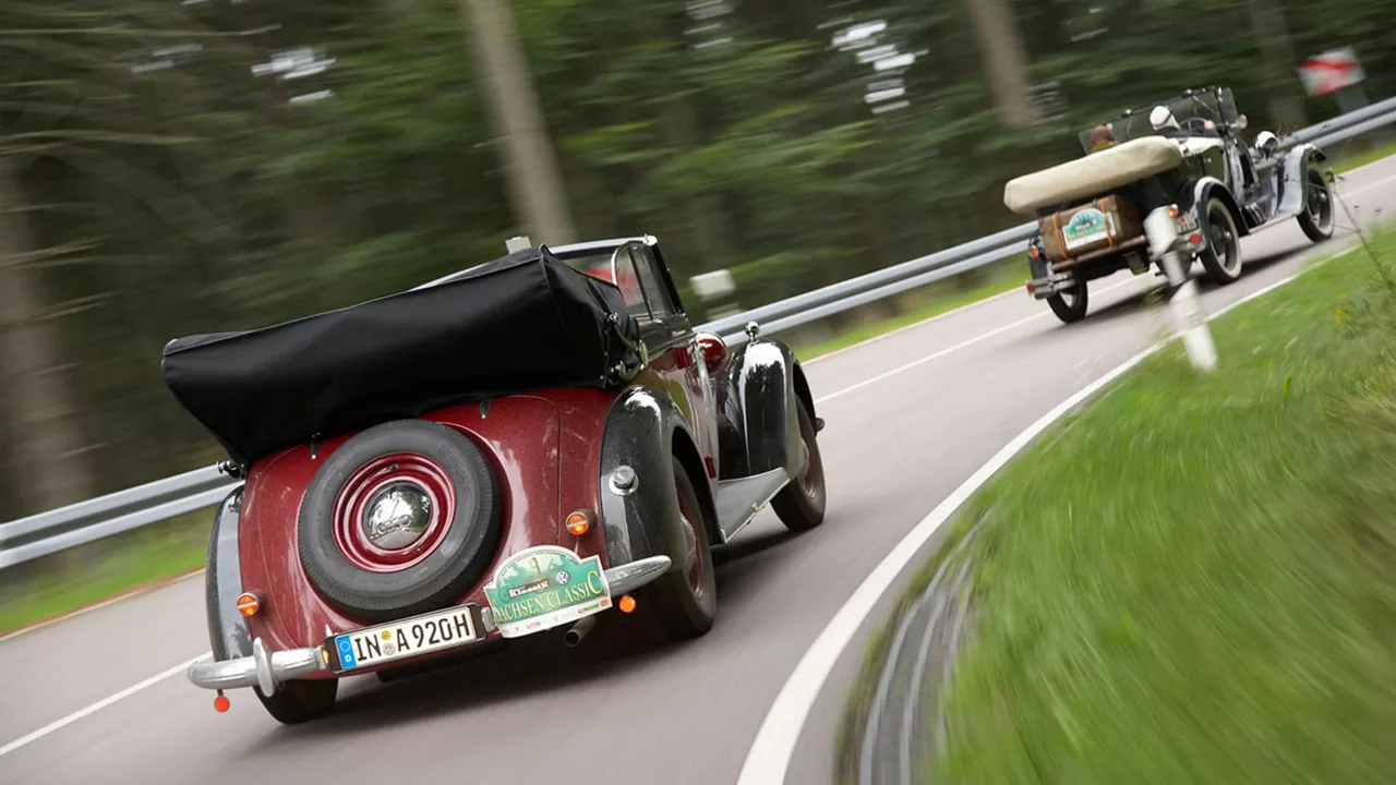 Zwei Fahrzeuge fahren schnell um eine Kurve. Der Hintergrund ist verschwommen.