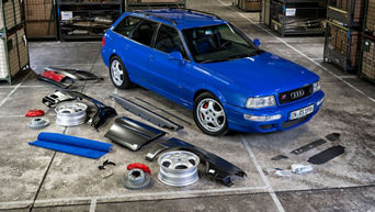 Ein blau lackiertes Audi Modell steht in einer Werkstatt neben Ersatzteilen