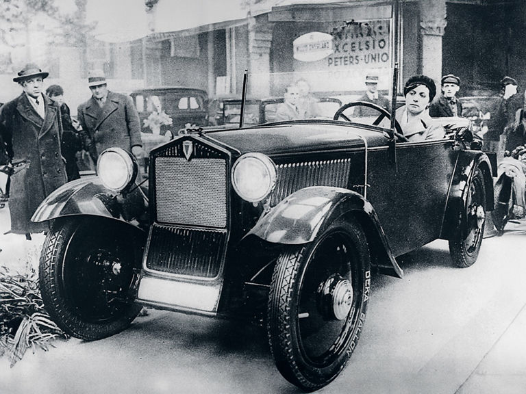 Schwarz-weiß-Aufnahme einer Frau, die den DKW Front F 1 fährt, umgeben von Leuten