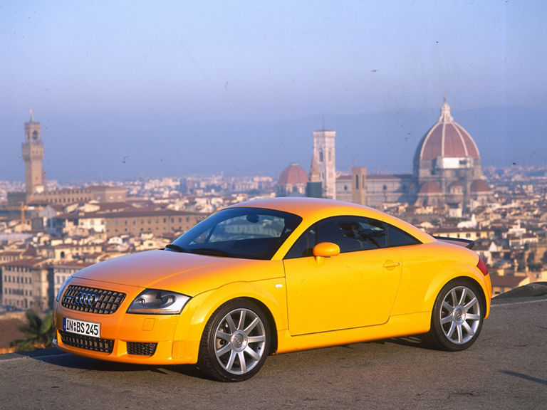 Ein gelber Audi TT Coupé 3.2 quattro vor einer Stadtkulisse