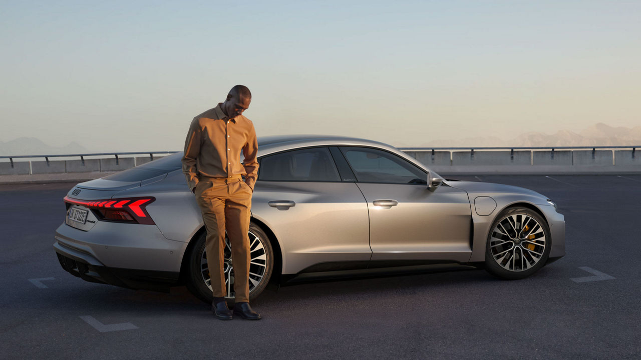 Mann lehnt lässig an einem silbernen Audi e-tron GT