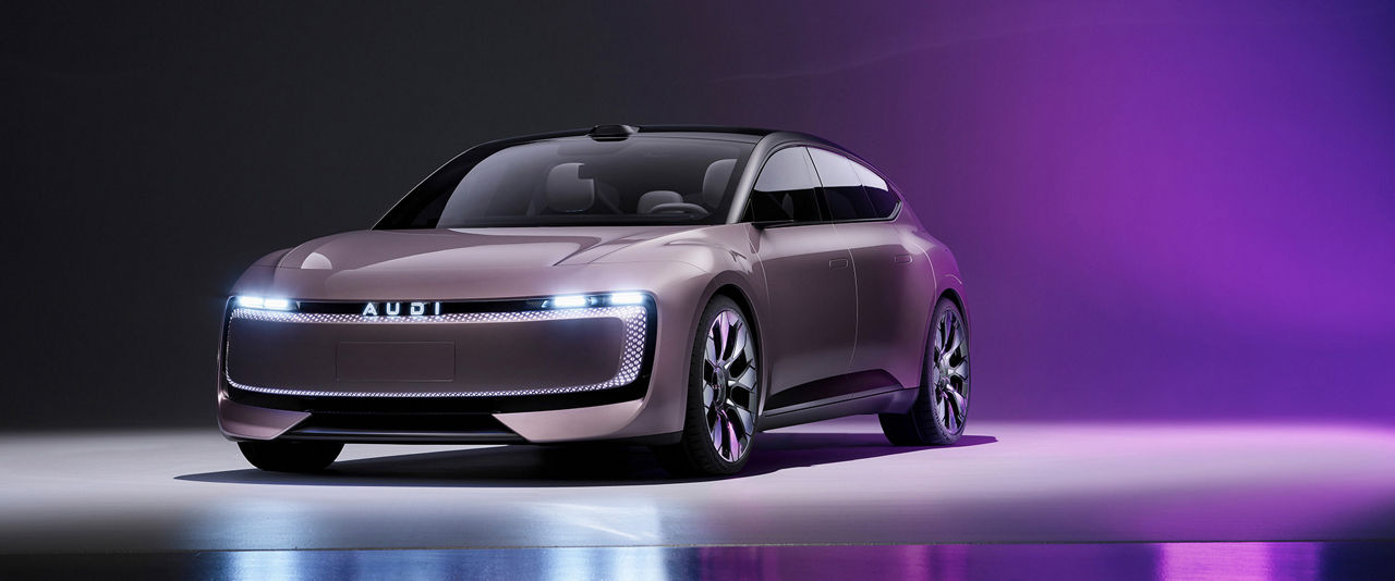 The Audi concept car with its futuristic design and continuous LED light signature stands in a dark studio environment with purple lighting reflected on the floor.        
