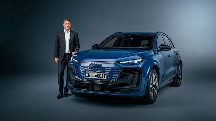 Gernot Döllner steht neben einem blau lackierten Audi Q6 e-tron