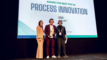 Drei Personen auf der Bühne des Venture Clienting Awards vor einer Leinwand.