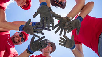 5 people stand in a circle and hold their hands in the middle