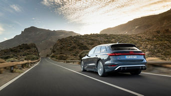 An Audi S6 Avant e-tron in plasma blue metallic on a road through the mountains