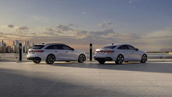 Audi A5 Avante-tron and Audi A5 Sedan e-tron are parked on asphalt at outdoor charging stations.
