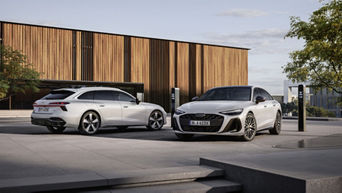 An Audi A6 Avant e-hybrid quattro and an Audi A6 Sedan e-hybrid quattro in glacier white on a paved courtyard