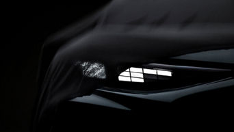 A black cloth lies halfway over the shining headlights of the black Audi Q3.