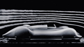 Side view of a fully clad, historic Audi racing car against a dark background. Streamlines are indicated above the vehicle.
