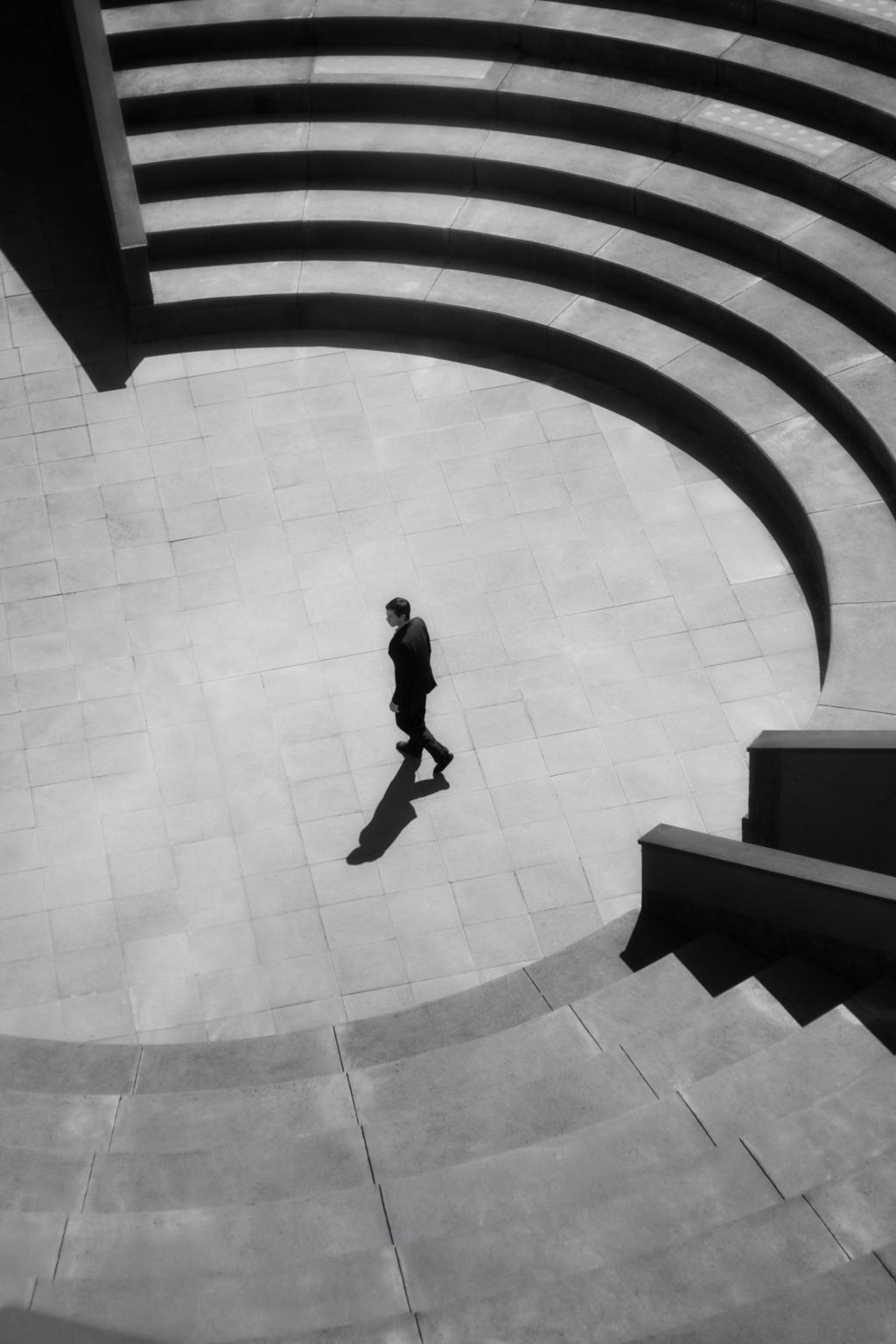 Harris Dickinson, photographed from above, walks across an empty square.