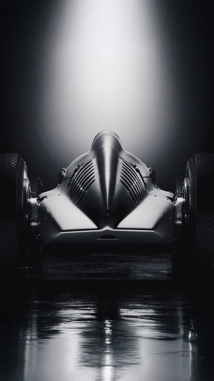 Rear view of a historic Audi racing car against a dark background.