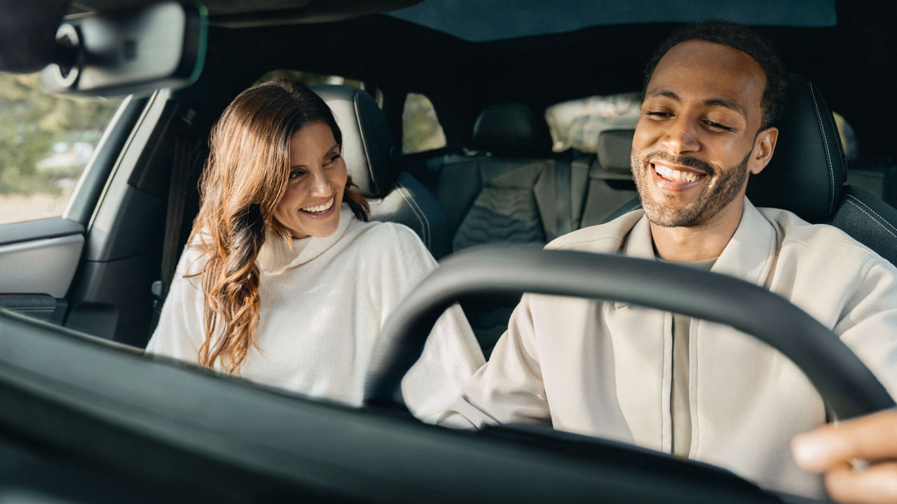 Couple sitting happily laughing in the front seats of their Audi