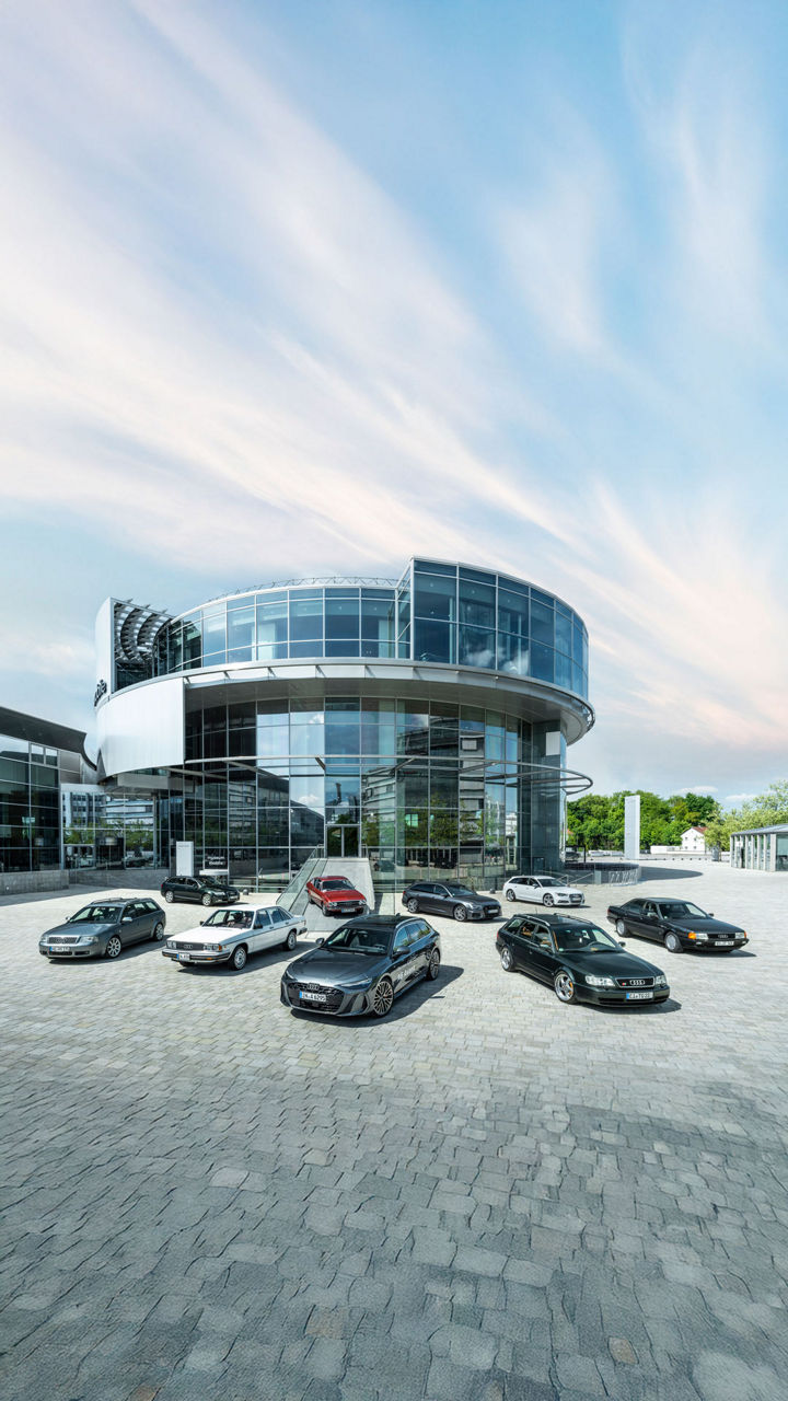 Audi C Series models are lined up in a star shape in front of the round glass façade of the Audi museum mobile.