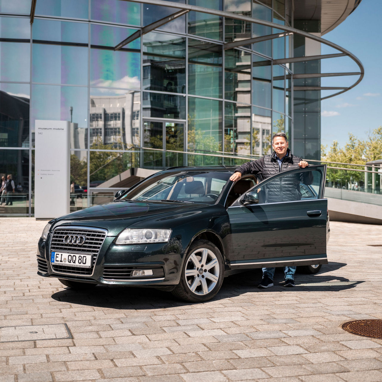 Stephan Schwantner stands in the ajar driver's door of his black C6. He is wearing a dark quilted jacket.