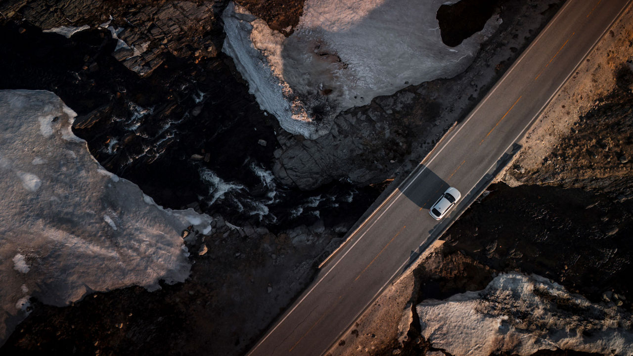 Luftbild des weißen Audi A6 Sportback e-tron auf einer Brücke zwischen Felsschluchten.
