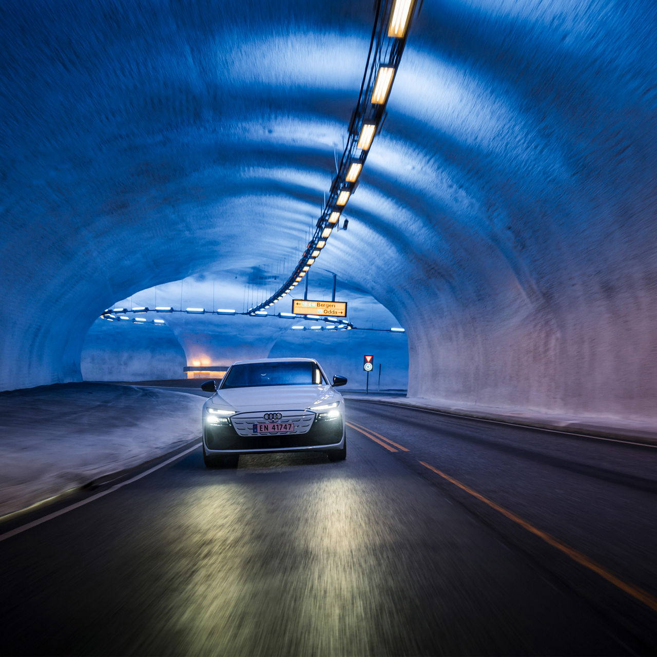 Der weiße A6 Sportback e-tron performance wird durch die Deckenbeleuchtung des Vallaviktunnels in blaues Licht getaucht.