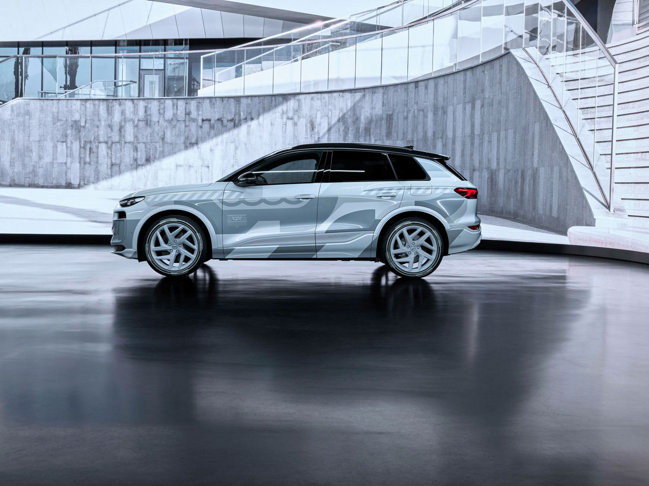 Audi Q6 e-tron concept in silver-grey foiling in front of a textured concrete wall