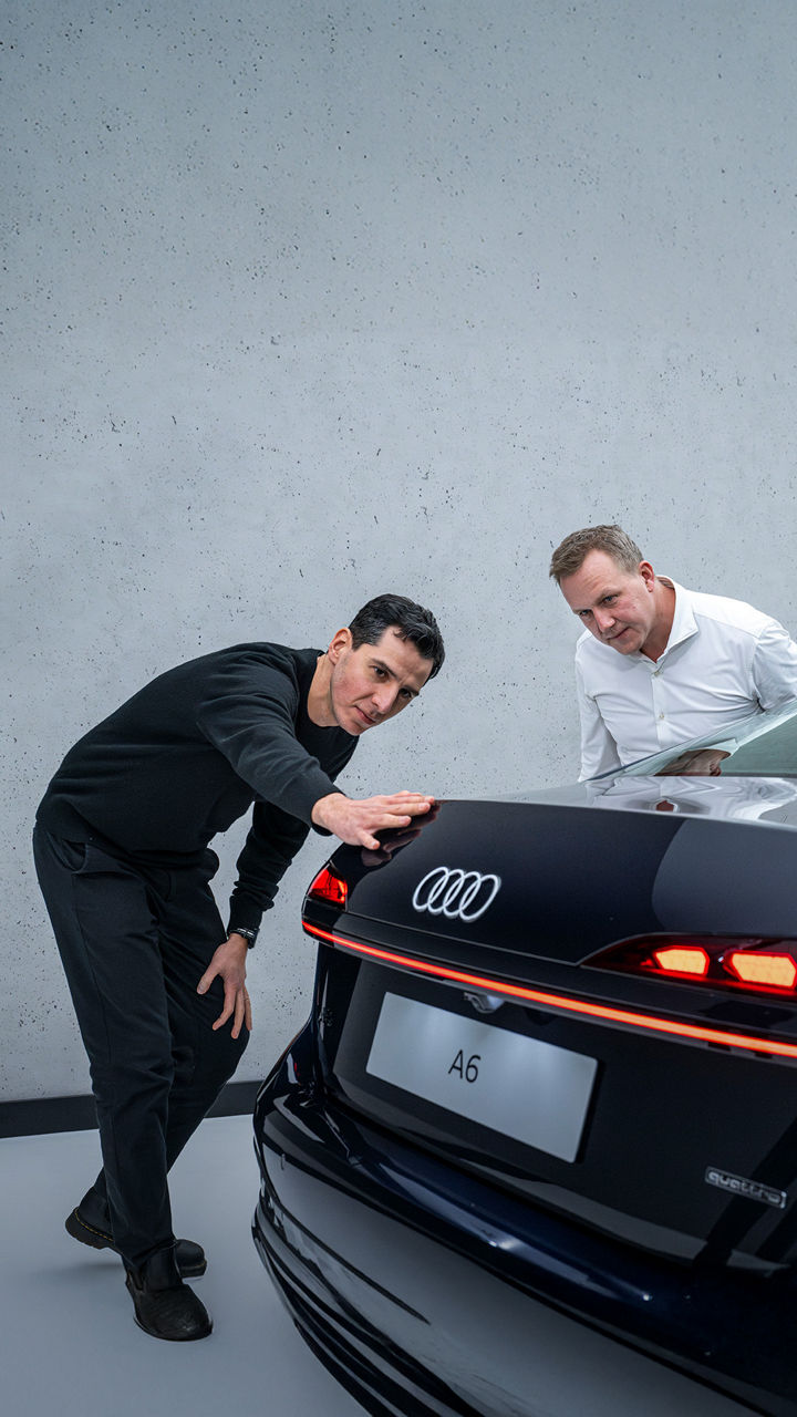 Experts in conversation. Designer Francesco d’Amore runs his hand along the rear line of the black Audi A6 Sedan, with aerodynamicist Sebastian Weiper standing next to him.