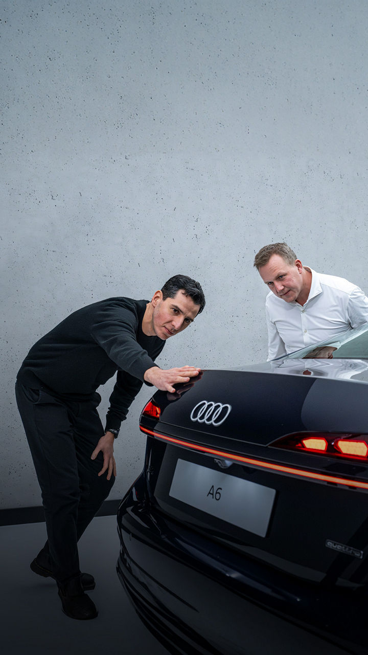 Experten im Gespräch. Designer Francesco d’Amore streicht mit der Hand entlang der Hecklinie des schwarzen Audi A6, neben ihm Aerodynamiker Sebastian Weiper.