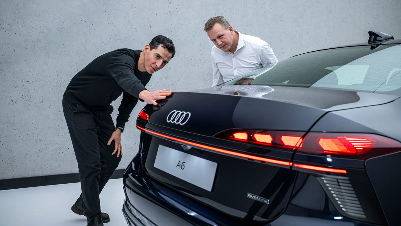 Experts in conversation. Designer Francesco d’Amore runs his hand along the rear line of the black Audi A6 Sedan, next to him aerodynamicist Sebastian Weiper.