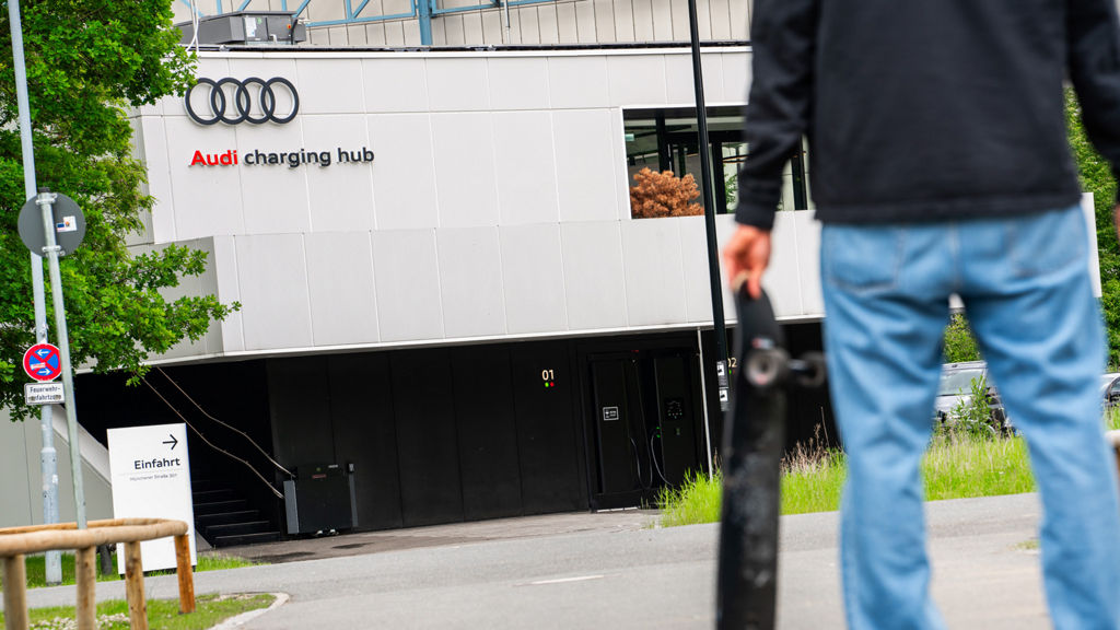 Ein Mann steht vor dem Audi charging hub mit einem Skateboard in der Hand
