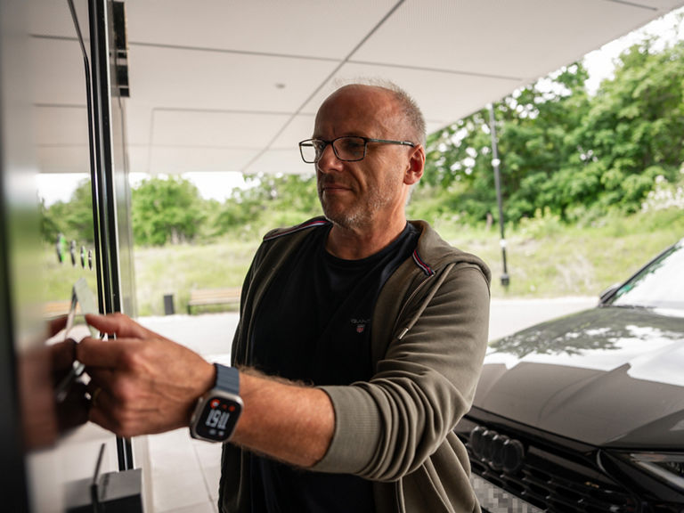 Ein Mann hält eine Karte an die die NFC-Fläche des Audi charging hubs
