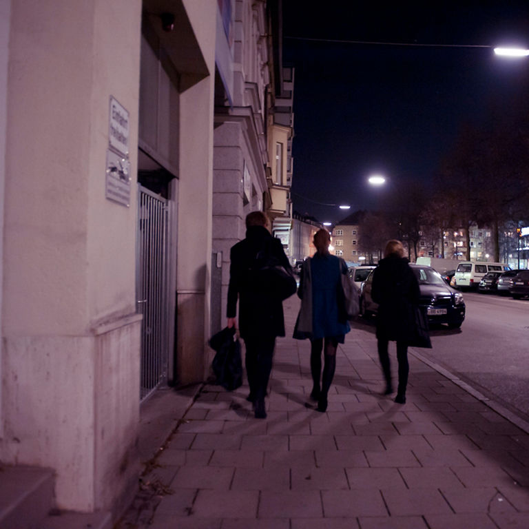 People walking in the dark on a sidewalk