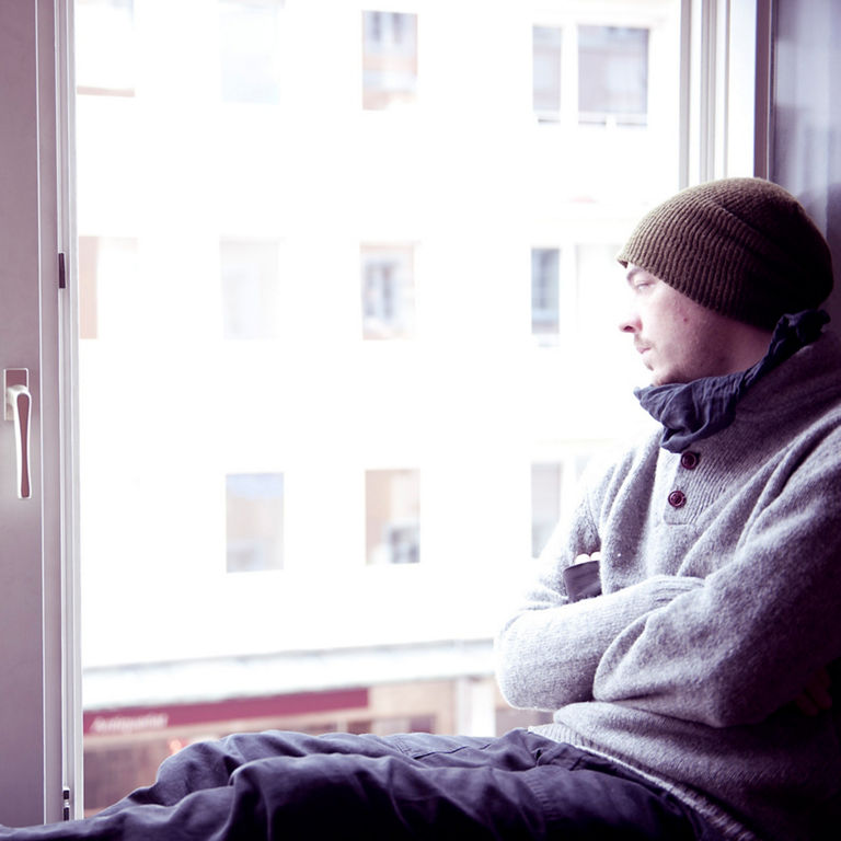 A man sits on a windowsill and looks outside